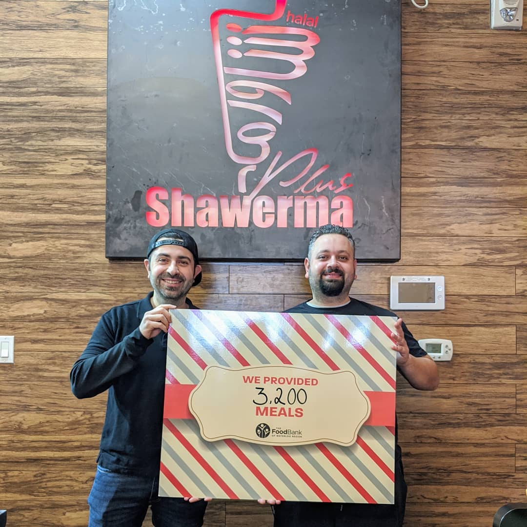 Shawerma Plus team holding a Food Bank of Waterloo Region sign celebrating 3,200 meals provided