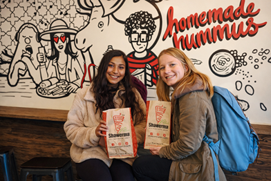 Happy customers holding their Shawerma Plus orders